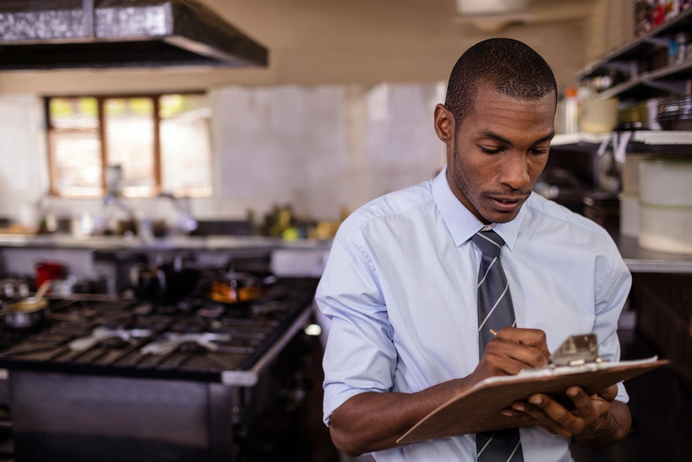 Mid-adult,African,American,Man,Using,Clipboard,In,Commercial,Kitchen,,With